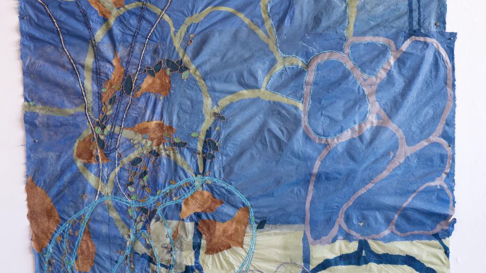 Abstract design in yellows, blue, orange and pink on a puckered blue and white background. 